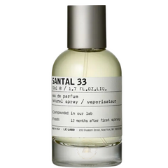 Le Labo Santal 33 Eau de Parfum in a clear glass bottle with light yellow liquid, featuring its iconic white label with bold black lettering, a sleek silver cap, and referencing its New York origin