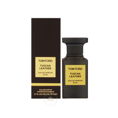 Photograph by Tom Ford depicting a dark brown glass Tom Ford Tuscan Leather Eau de Parfum 50 ML bottle next to its matching rectangular packaging box, both with prominent gold yellow labels clearly displaying the fragrance name