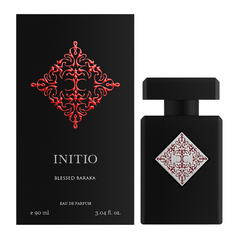 Initio brand perfume product image displaying the matte black Initio Blessed Baraka Eau de Parfum bottle with its silver and red ornate diamond emblem next to its coordinating matte black box featuring a larger embossed red ornate diamond pattern