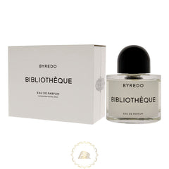 Product photography Byredo Bibliothèque Eau de Parfum in a clear glass bottle with a black dome cap and white label stands next to its matte white box displaying similar black text and a subtle embossed pattern
