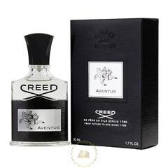 Photography of a Creed Aventus 50ml Eau de Parfum clear glass bottle with a black cap and ribbed texture, displayed next to its matching black textured box, both featuring the iconic silver rider on horseback emblem and Creed Aventus branding on a white background