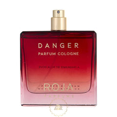 Product photo of Roja Parfums Danger Parfum Cologne, a rectangular glass bottle with a deep red to pink gradient liquid, gold spray cap, and prominent gold text DANGER PARFUM COLOGNE and mirrored Roja branding