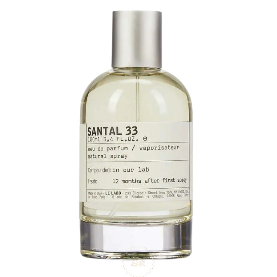 Product photography Le Labo Santal 33 eau de parfum bottle 100ml with a distinctive white paper label detailing 'Compounded: in our lab' and a silver metallic spray cap on a clear glass vessel