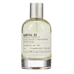 Product photography Le Labo Santal 33 eau de parfum bottle 100ml with a distinctive white paper label detailing 'Compounded: in our lab' and a silver metallic spray cap on a clear glass vessel