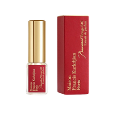 Fragrance by Maison Francis Kurkdjian Baccarat Rouge 540 Extrait de Parfum Paris featuring a clear glass travel spray bottle with a gold cap and red label alongside its vivid red box with gold lettering