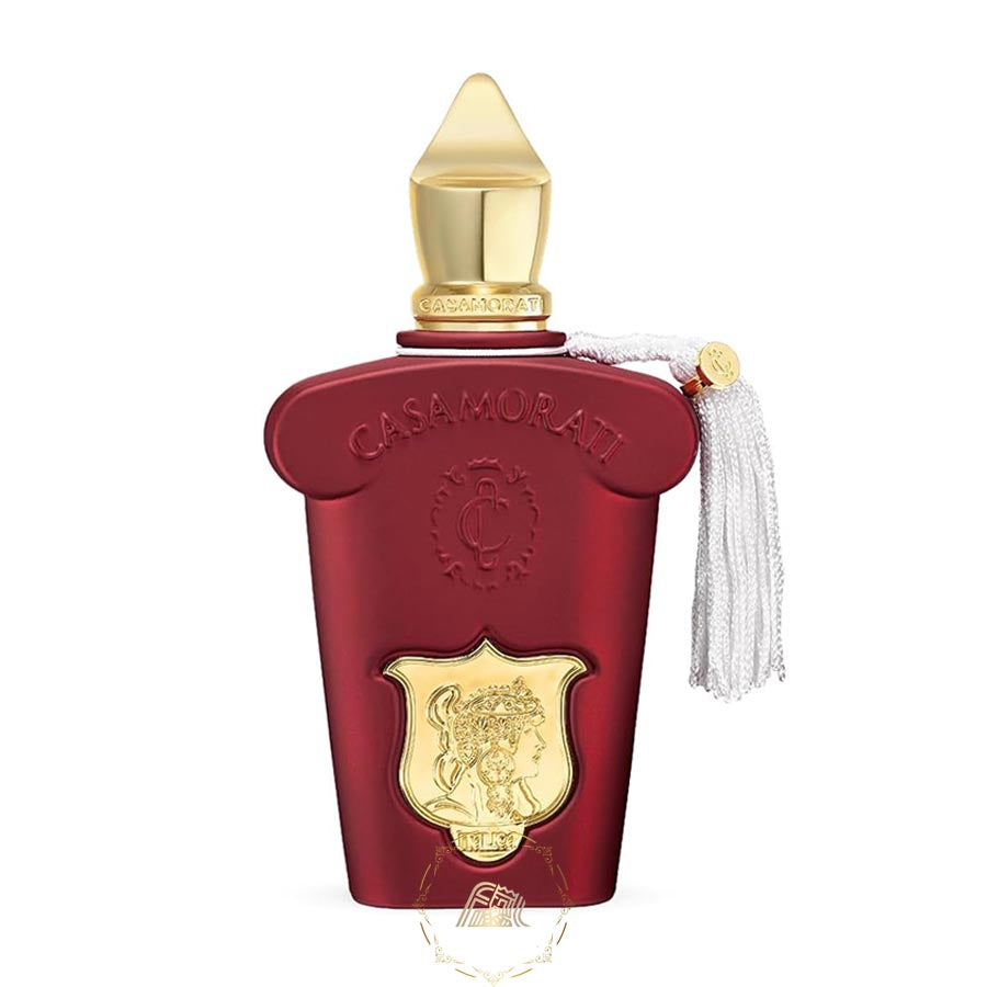 Casamorati Lira perfume bottle featuring a deep red matte finish, an ornate gold pointed cap, a gold shield emblem with a classical female profile, and an elegant white silk tassel