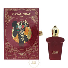 Product photo by Casamorati of the deep red Casamorati Italica perfume box featuring an art nouveau illustration of a woman in a jeweled headdress and gold ornate patterns, alongside a matching deep red bottle with a prominent gold cap and "ITALICA" in gold text on a white background