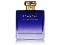 Photograph of a Roja Parfums Scandal Parfum Cologne bottle featuring a dark blue to clear gradient glass, a prominent gold faceted crown cap, and metallic gold lettering on a clean white background