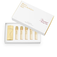 Product photography of a Maison Francis Kurkdjian Paris Baccarat Rouge 540 Eau de Parfum travel set, featuring a white box with a gold-edged lid, one large gold geometric atomizer, and five smaller gold-capped clear glass vials of light amber perfume