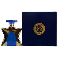 A Bond No 9 NYC perfume set featuring an ornate gold-patterned bottle with a central blue arch and stopper next to its deep navy blue box adorned with a prominent gold circular NYC emblem