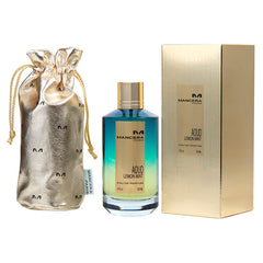 Product photography of Mancera Paris Aoud Lemon Mint Eau de Parfum set showcasing a blue to green ombré bottle with a gold cap, a matching textured gold box, and a metallic gold drawstring pouch with repeating M logos