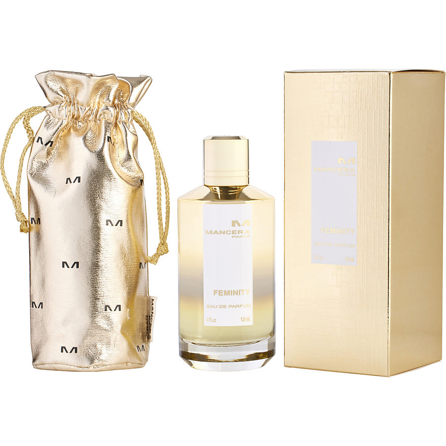 Product photograph of Mancera Feminity Eau de Parfum set featuring a shiny gold drawstring pouch, a clear glass bottle with a golden cap, and a matching textured gold box displayed on a white background