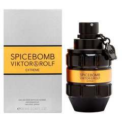 Product photography by Viktor & Rolf of Spicebomb Extreme Eau de Parfum for men, featuring a distinct black grenade-shaped bottle with an orange label next to its silver-grey packaging box