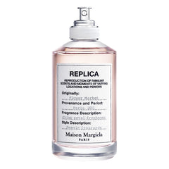 Maison Margiela Replica Flower Market perfume bottle features a clear glass design with pale pink liquid, a minimalist white label detailing "Paris, 2011" and "crisp petal freshness"