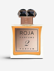 Product photograph, Roja Parfums, featuring a clear rectangular 2 Parfum bottle with amber liquid, a rose gold label, and a prominent black faceted crystal cap