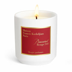 Maison Francis Kurkdjian Paris fragranced candle a lit candle in a minimalist white ceramic vessel featuring a bold red label with gold trim displaying Baccarat Rouge 540 in elegant script