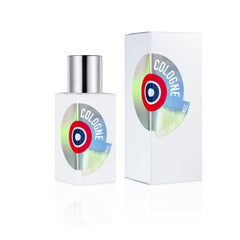 Product photography of an Etat Libre d'Orange Cologne bottle with a silver cap and its matching box on a white reflective surface, both featuring a round metallic holographic label with a red, blue, and black target design, displaying "Cologne" and "Etat Libre d'Orange" text