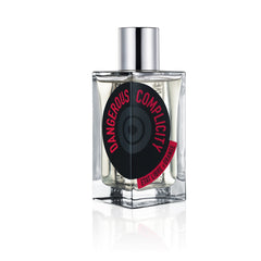 Product photo, Etat Libre d'Orange Dangerous Complicity perfume bottle featuring a clear rectangular glass design, a silver cap, and a black vinyl record-inspired label with bold red text