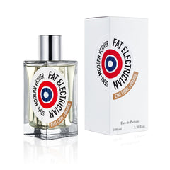 Product photography by Etat Libre d'Orange of a Fat Electrician perfume bottle and its white box on a reflective white surface, featuring a clear square bottle with a shiny silver cap and both items displaying a prominent red, white, and blue target-style roundel label with "FAT ELECTRICIAN" "SEMI-MODERN VETIVER" and "ETAT LIBRE D'ORANGE" on a brown banner, the box also showing "100 ml 3.38 fl.oz"