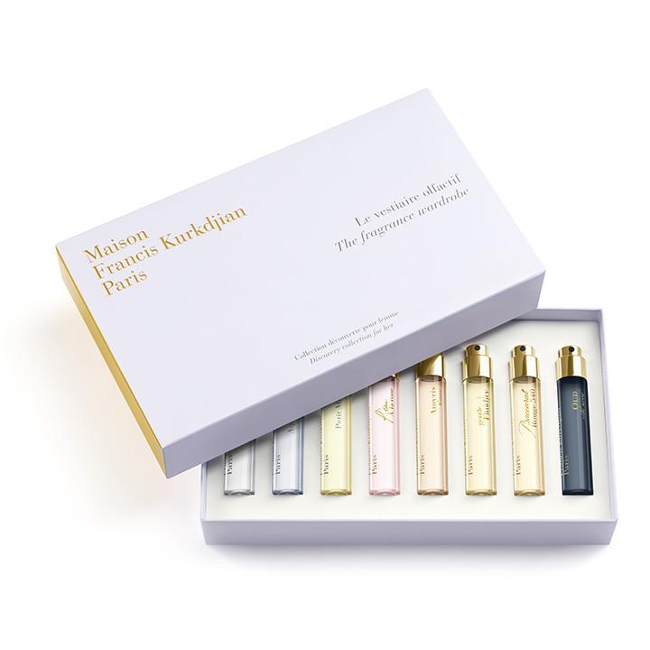 Maison Francis Kurkdjian Paris white fragrance wardrobe discovery collection for her box with elegant gold lettering, revealing eight miniature perfume vials in varied light pink, yellow, and dark blue shades with shining gold caps
