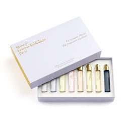 Maison Francis Kurkdjian Paris white fragrance wardrobe discovery collection for her box with elegant gold lettering, revealing eight miniature perfume vials in varied light pink, yellow, and dark blue shades with shining gold caps