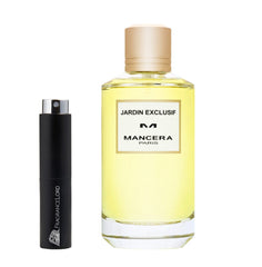 Photograph of a clear glass Mancera Jardin Exclusif Paris perfume bottle with light yellow liquid and a gold cap alongside a smaller black FragranceLord decant spray bottle featuring a silver sprayer and distinct logo