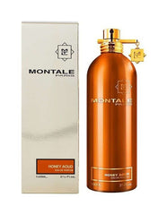 Product photography of Montale Paris Honey Aoud Eau de Parfum showing a metallic bronze orange cylindrical bottle with a gold cap and M charm next to its white box, both clearly displaying the 'Honey Aoud Eau de Parfum 100ML' label on a white background