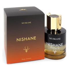 Nishane Muskane Demi Extrait perfume bottle with a gold cap and amber liquid alongside its black to orange gradient box featuring gold text and a distinct stag logo