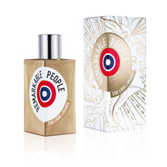 Product photography of Etat Libre d'Orange Remarkable People perfume, showcasing a gold bottle with a silver cap and a distinctive red, white, and blue target emblem, accompanied by its white box featuring intricate gold line art