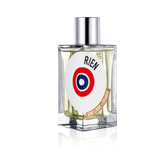 Product photo of Etat Libre d'Orange Rien perfume bottle in clear square glass with a silver cap and a white circular label displaying 'RIEN' in black over a red and blue target motif with 'ETAT LIBRE D'ORANGE' on a curved brown banner