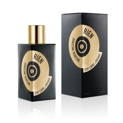 Product photo, Etat Libre d'Orange black perfume bottle with shiny gold cap and its matching box, both featuring a gold circular label with "Rien Intense Incense" and a central black target graphic on a reflective white surface