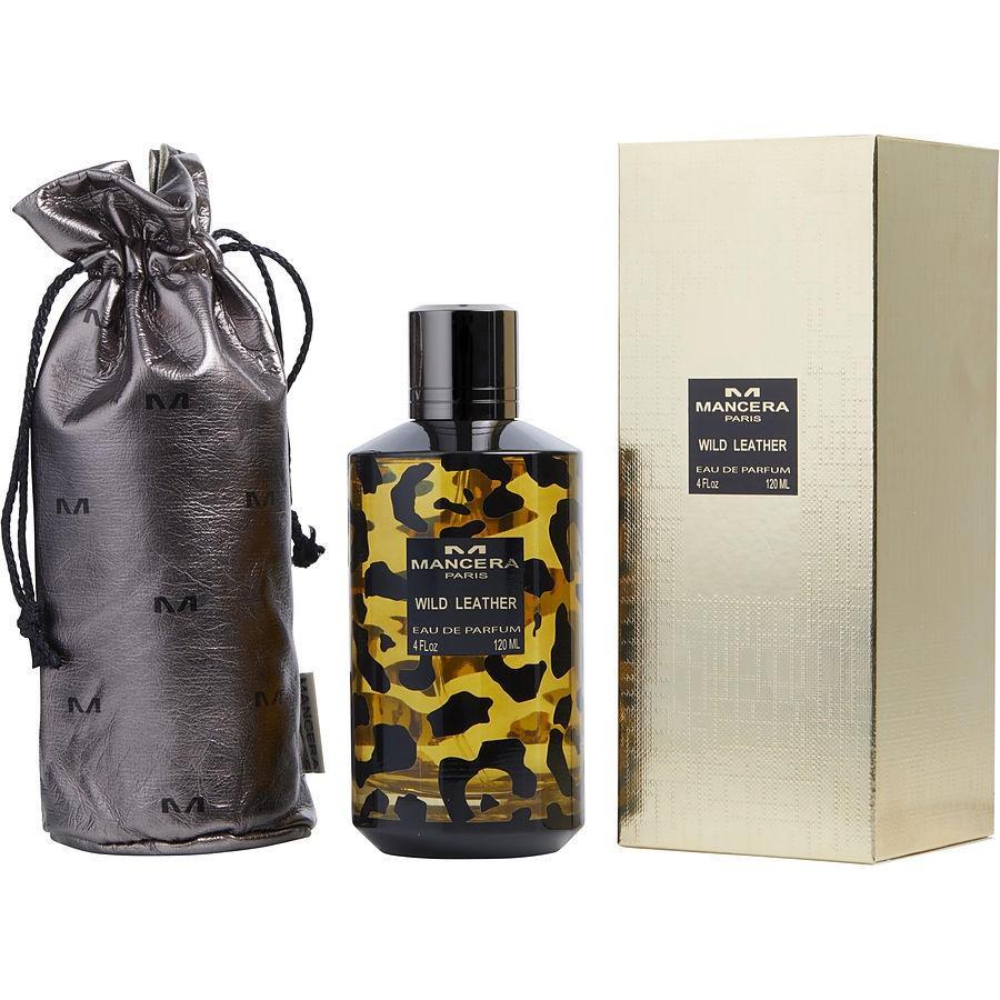 Product photography by Mancera Paris featuring Wild Leather perfume in a leopard print bottle next to a metallic gray drawstring pouch with M logos and a textured gold box