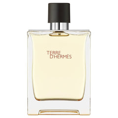 Still life product photograph of the Hermès Terre d'Hermès fragrance bottle featuring a clear rectangular glass design, amber-toned liquid, a dark brown cap, and prominent red text on a pristine white background