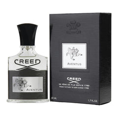 Product photo of a Creed Aventus perfume featuring a clear glass bottle with a black sculptural cap, 'CREED' logo, and a silver label depicting a rider on a horse, displayed next to its textured black box also showing the rider emblem and '50 ML' volume