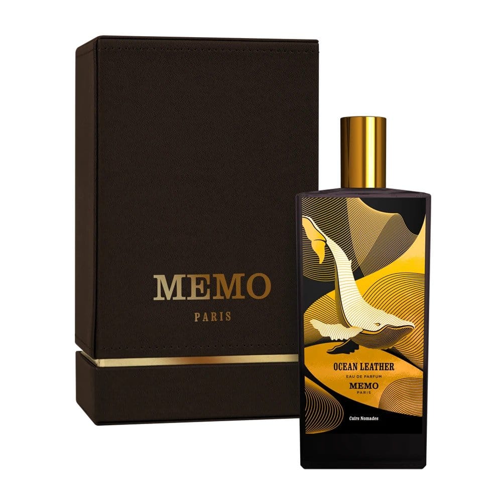 Product photo by MEMO PARIS of an Ocean Leather Eau de Parfum bottle and dark brown box from Paris displaying a white whale illustration over gold and black geometric patterns with gold branding