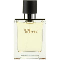 Product photo by Hermès of a Terre d'Hermès men's fragrance bottle on a white background displaying a clear rectangular glass bottle with a black cap amber liquid and the name in orange text