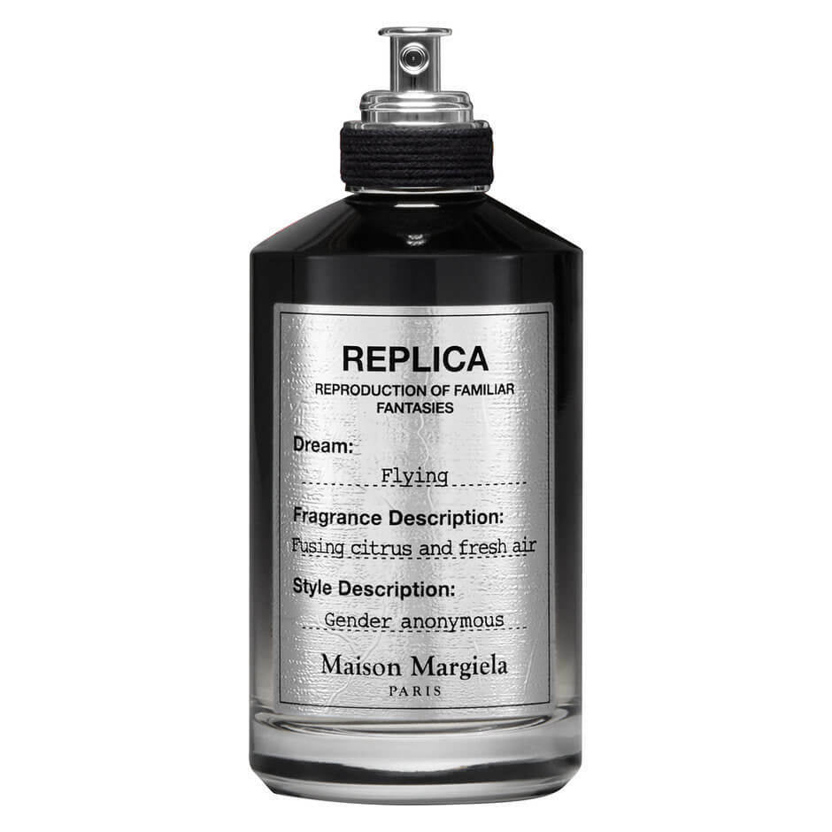 Maison Margiela Replica fragrance bottle, a dark opaque vessel with a silver label featuring REPLICA branding, the dream Flying, and a fragrance description Fusing citrus and fresh air gender anonymous