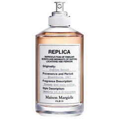 Maison Margiela Replica Coffee Break perfume bottle designed in Paris, featuring amber liquid in a clear glass bottle with a white typewritten label noting "Stockholm, 2007" provenance and a "creamy and cozy coffee" fragrance description, finished with a silver spray cap