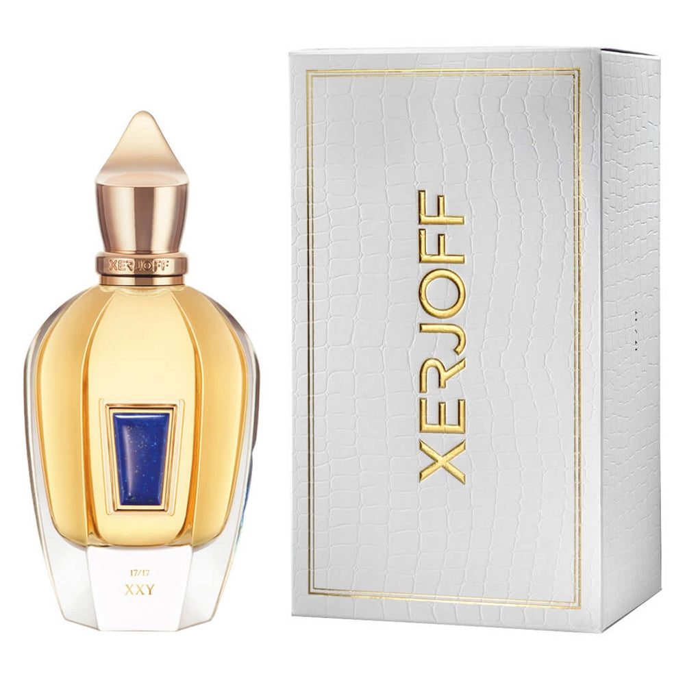 Product photography of a Xerjoff XXY perfume bottle featuring gold liquid, a blue lapis lazuli inlay, and a pointed gold cap, alongside its white crocodile-textured box with gold Xerjoff branding