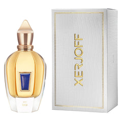 Product photography of a Xerjoff XXY perfume bottle featuring gold liquid, a blue lapis lazuli inlay, and a pointed gold cap, alongside its white crocodile-textured box with gold Xerjoff branding