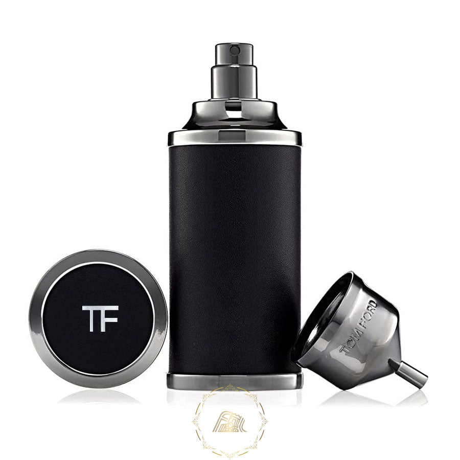 Tom Ford luxury fragrance set featuring a black leather-wrapped cylindrical atomizer with gunmetal top and base, a round cap displaying the TF logo, and a small metal funnel engraved with TOM FORD